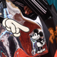 A silver handbag showing a large gloved figure pointing at a mickey mouse character.